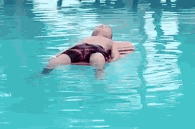 a child is laying on a raft in a swimming pool .