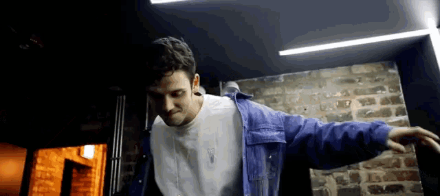 a man in a purple jacket is dancing in a dark room .