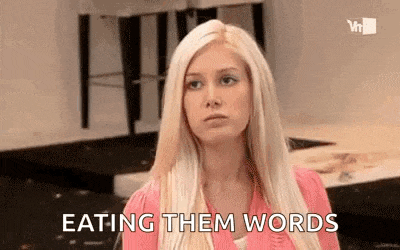 a woman is eating them words while sitting in a kitchen .
