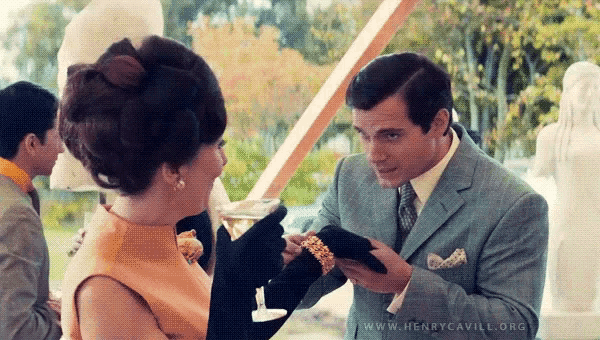 a man in a suit and tie is giving a woman a bracelet ..