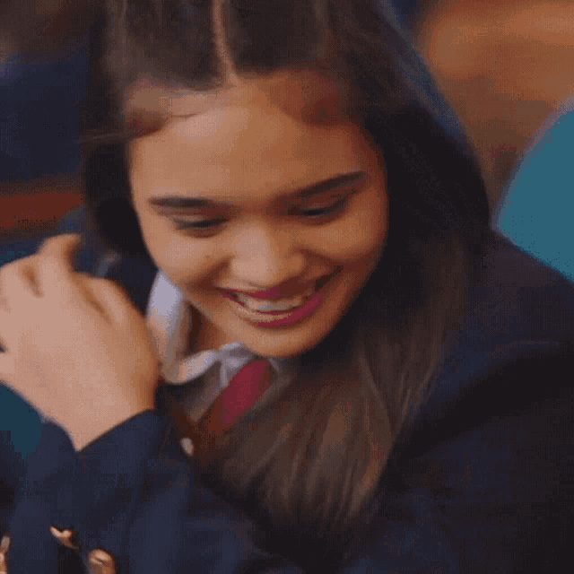 a girl in a school uniform is smiling and hugging someone
