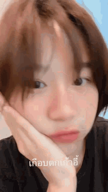 a woman with short hair is making a funny face with her hand on her face and a caption in a foreign language .