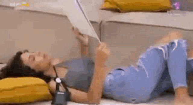 a woman is laying on her stomach on the floor reading a book .