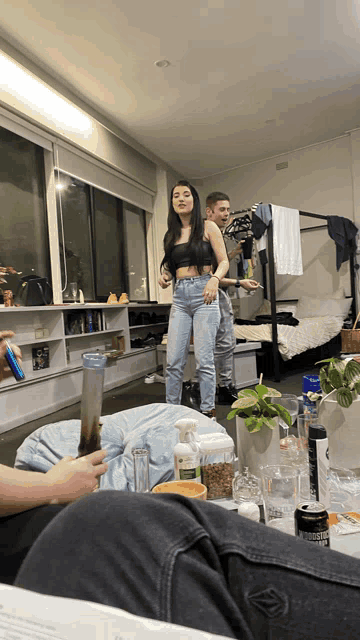 a woman in a black top stands in a living room with a man