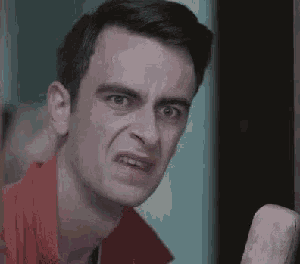 a man in a red shirt is making a funny face while standing next to a door .
