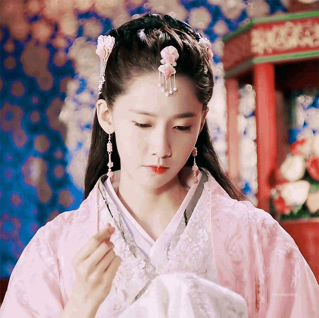 a woman wearing a pink and white kimono with a flower in her hair