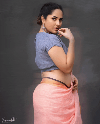 a woman wearing a gray top and a pink saree poses for a photo