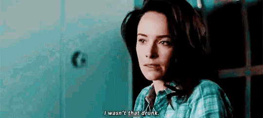 a woman in a plaid shirt is sitting in a dark room and says `` i wasn 't that drunk '' .
