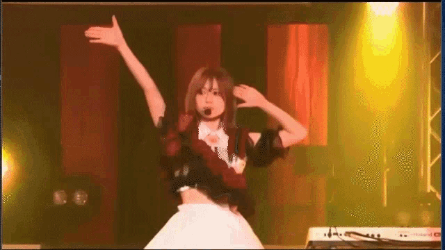 a woman is dancing on a stage with her arms in the air