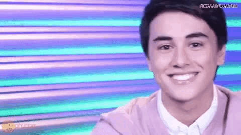 a young man is smiling for the camera in front of a purple and blue background .