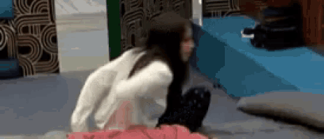 a woman is squatting on the floor in a room with a blue bed in the background .