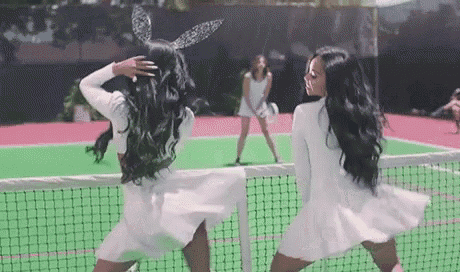 two women in white dresses are standing on a tennis court .