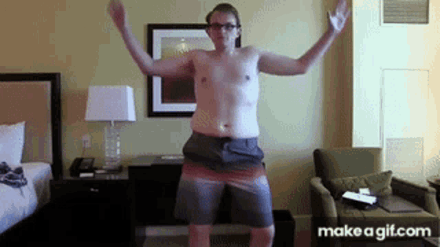 a shirtless man in shorts is dancing in a hotel room