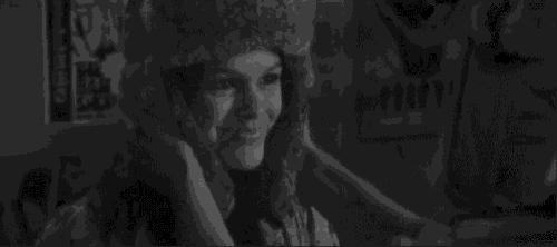 a man wearing a fur hat is standing next to a woman wearing a fur hat in a black and white photo .