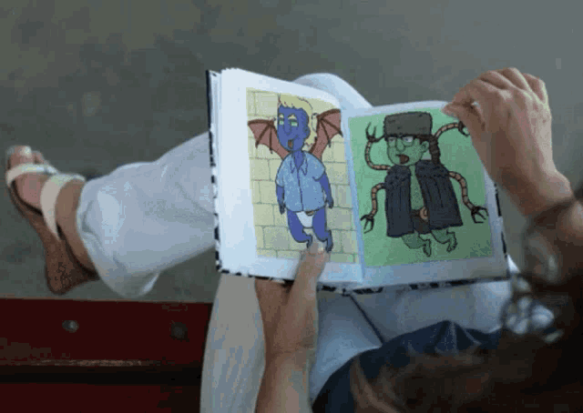 a person is reading a book with a picture of a monster on the cover