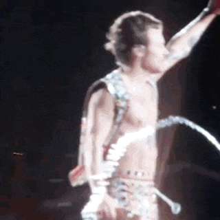 a man without a shirt is standing on a stage with a microphone .