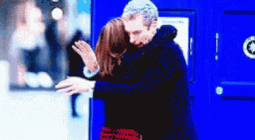 a man and a woman hugging in front of a blue building