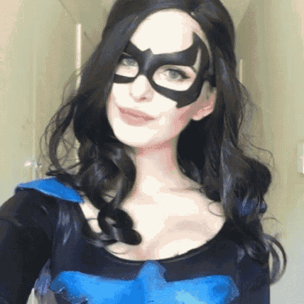 a woman in a superhero costume is taking a selfie with her mask on .
