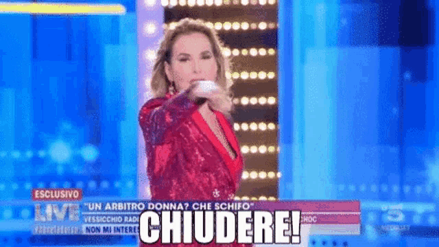 a woman in a red dress is standing in front of a sign that says ' chiudere ! '