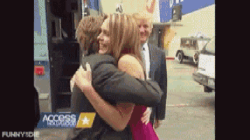 a woman in a red dress is hugging a man in front of a van that says access