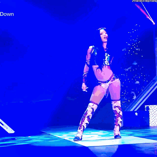 a woman in a wrestling outfit is standing on a stage with the word down on the bottom