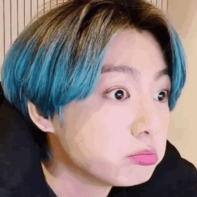 a close up of a person 's face with blue hair .