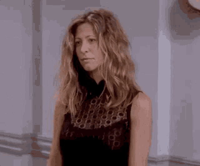 a woman in a black dress is standing in a hallway looking at the camera .
