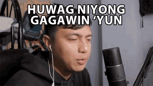 a man wearing headphones is sitting in front of a microphone and says " huwag niyong gagawin yun "