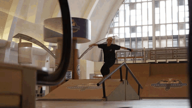 a skateboarder rides a railing in front of a sign that says red bull terminal