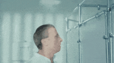 a man in a white lab coat is standing in front of a metal structure
