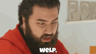 a man with a beard is wearing a red hoodie and says weip .