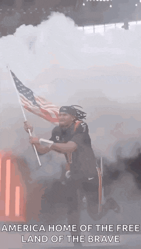 a man is kneeling down while holding an american flag in a stadium .