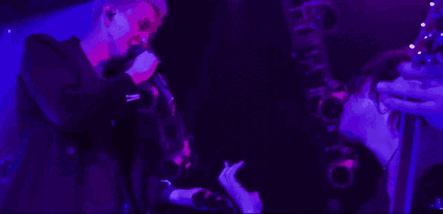 a man singing into a microphone while another man plays a guitar in a dark room