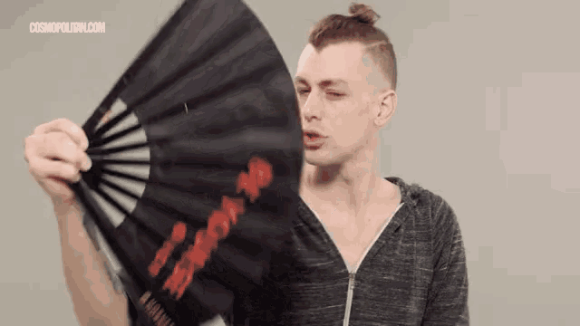 a man is holding a fan with chinese writing on it .