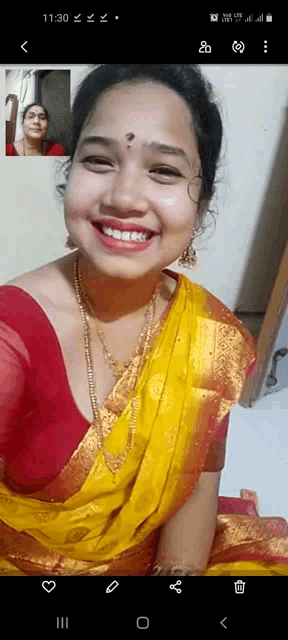 a woman in a yellow saree is smiling while taking a selfie .
