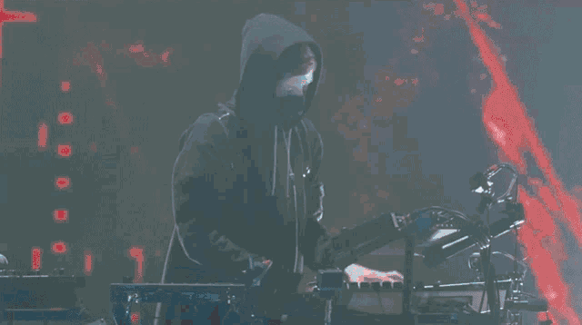 a man in a hooded sweatshirt playing a keyboard