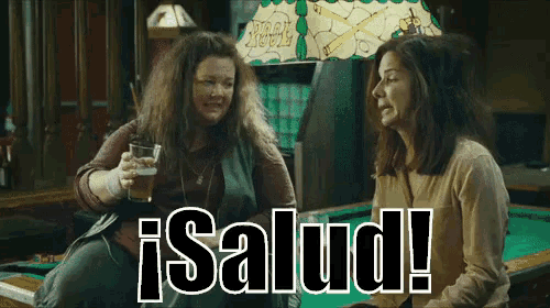 two women are sitting at a pool table and the words salud are on the bottom