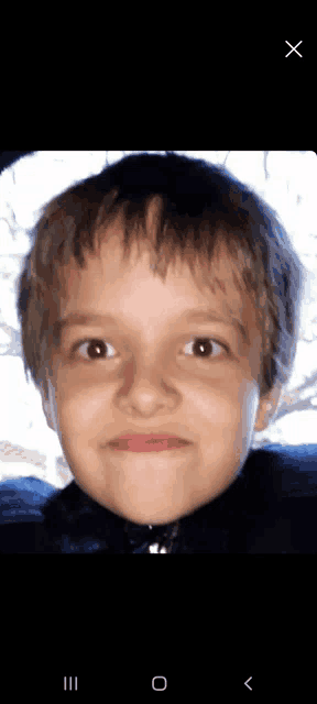 a close up of a young boy 's face with the letters x and o below it