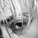 a black and white photo of a person 's eye behind a bunch of tall grass .