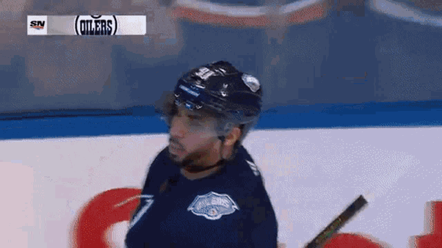 a hockey player wearing a helmet and a jersey that says oilers on it