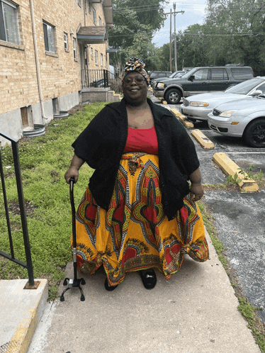 a woman with a cane is walking down a sidewalk in front of a building