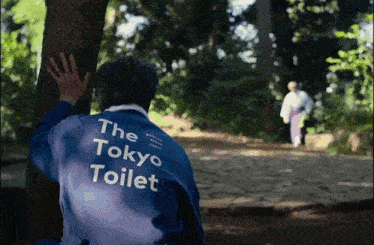 a man in a blue jacket that says the tokyo toilet on the back