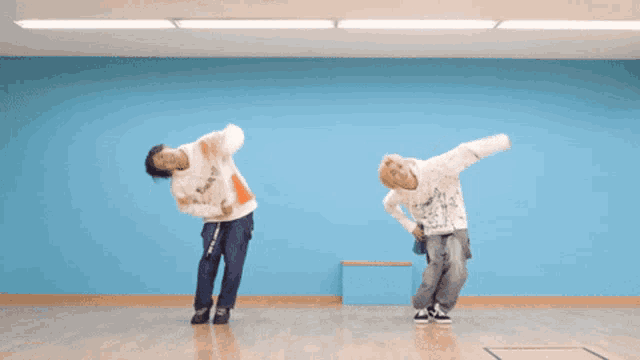 two men are dancing in front of a blue wall