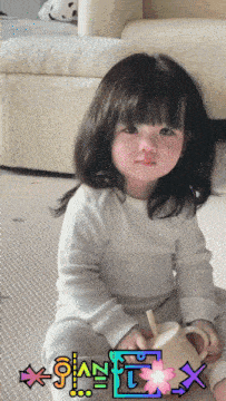 a little girl is sitting on the floor holding a yellow pitcher with a straw and the word x on the bottom