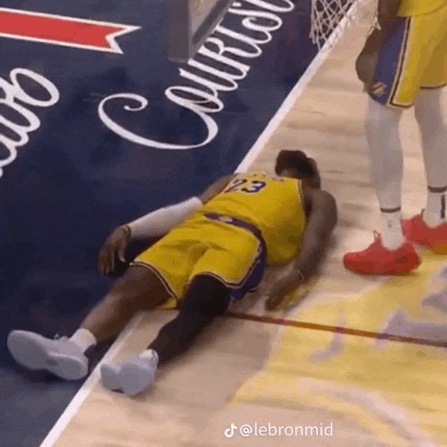 a basketball player with the number 23 on his jersey laying on the floor