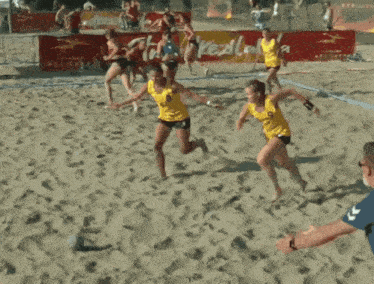 a group of people are playing volleyball on a sandy beach with a coca cola sign in the background