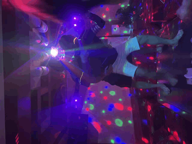 a group of people are dancing in a dark room with purple lights