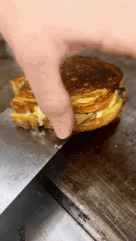 a person is holding a grilled cheese sandwich on a griddle