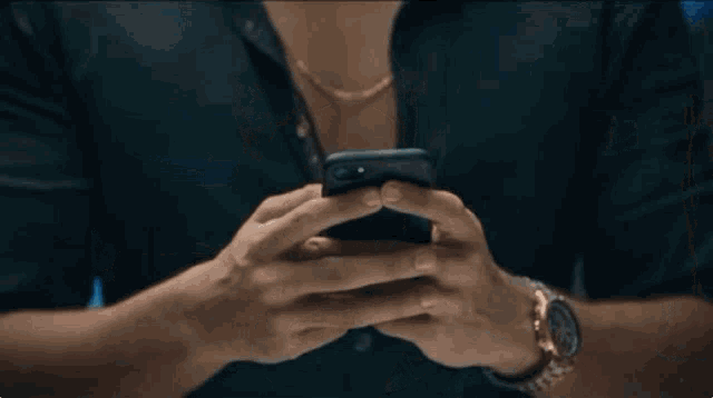 a man wearing a watch is holding a cell phone in his hands