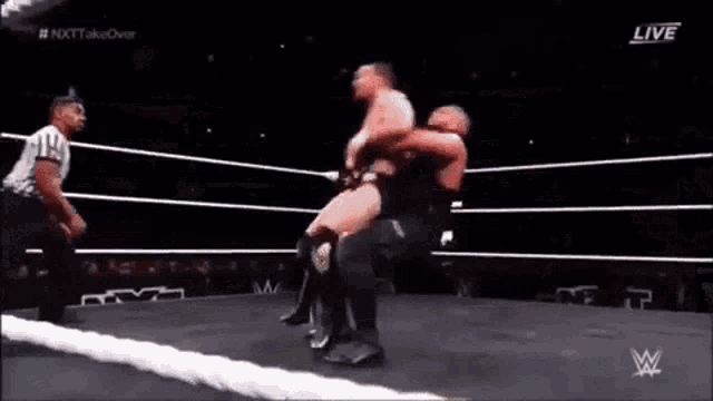a wrestler is doing a handstand in a wrestling ring during a match .